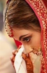 A bride in close-up, her veil and nose ring catching the light